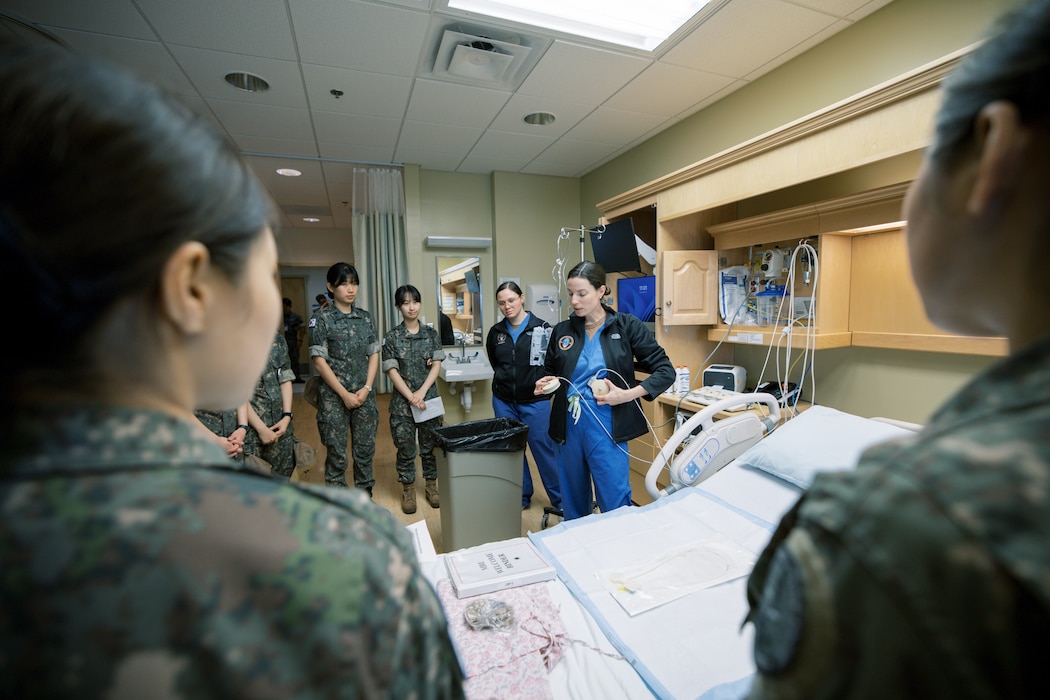 Hospitalman Nalani Cui and Lt. Hayley Wood demonstrate the setup and operation of intravenous infusion pumps for Republic of Korea (ROK) Military Nursing Academy cadets during a clinical skills rotation at U.S. Naval Hospital Guam, Nov. 14, 2025. The hands-on demonstration familiarized cadets with infusion equipment used in inpatient care settings and highlighted key principles of safe medication administration. (U.S. Navy photo by Hospital Corpsman 1st Class Clien Lester Guico.)