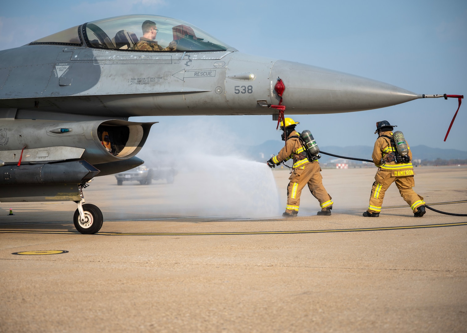 Firefighter simulating a fire near a F-16