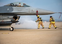 Firefighter simulating a fire near a F-16