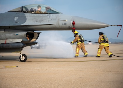 Firefighter simulating a fire near a F-16