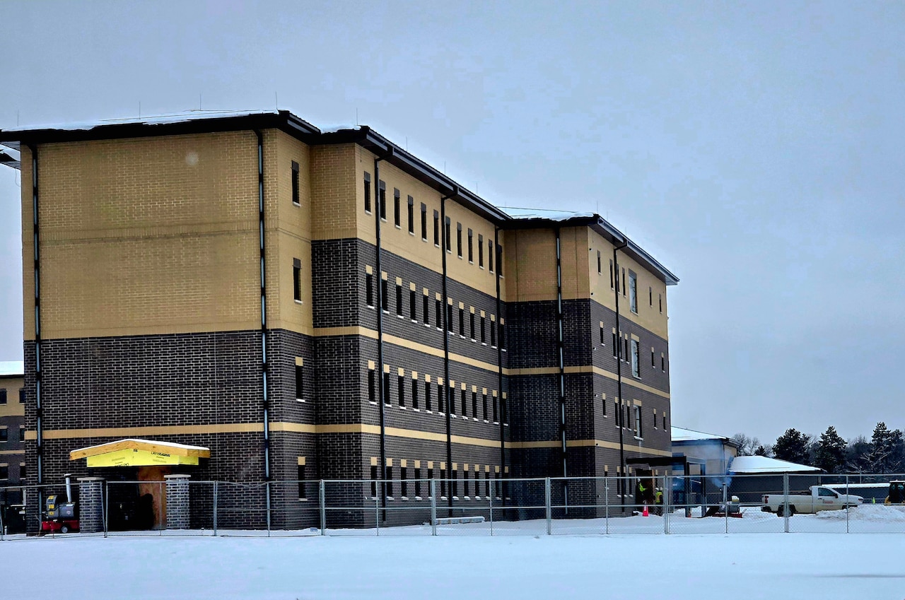 A four-story two-tone barrack is shown with snow on the ground.