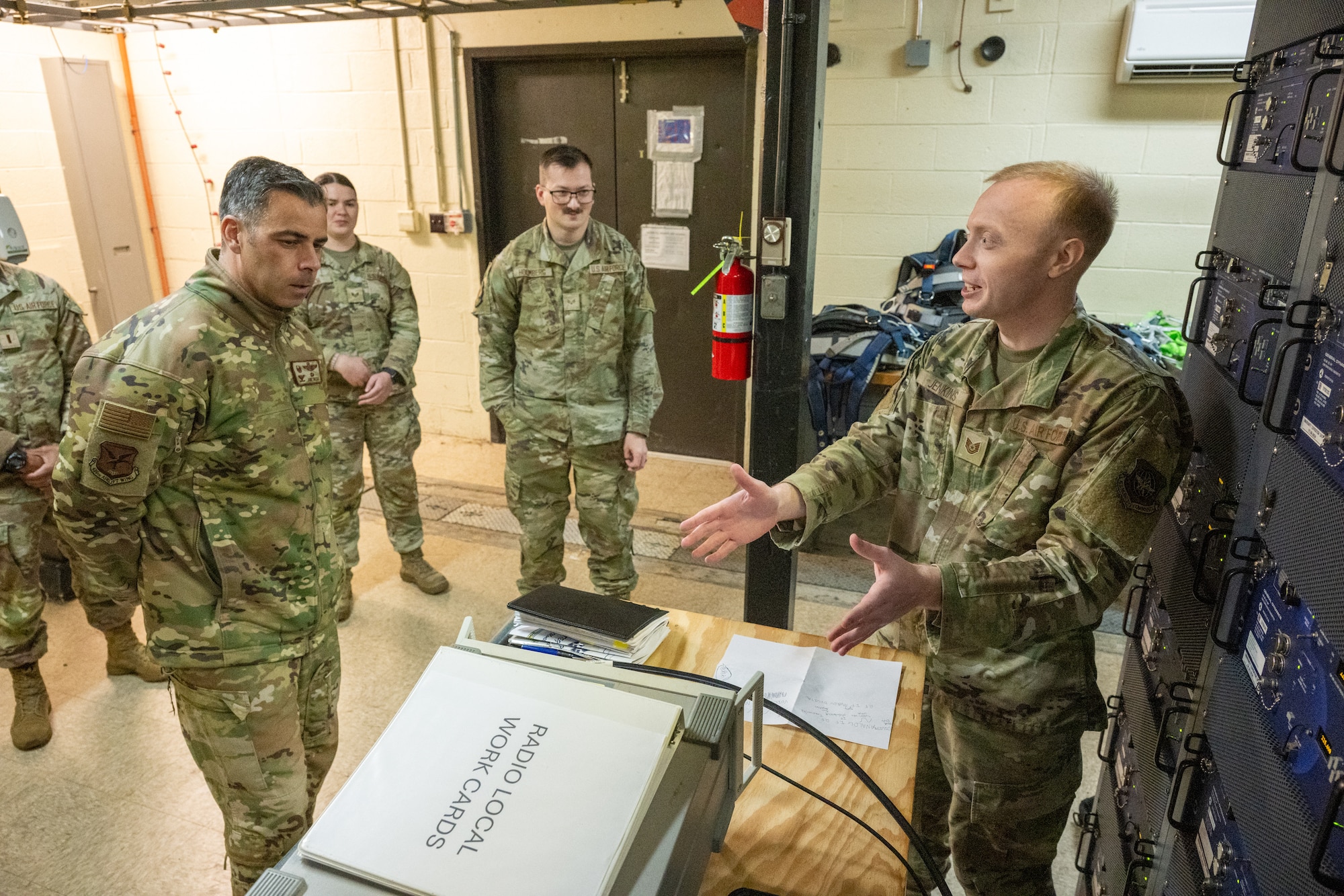 U.S. Air Force Tech Sgt. Daniel Jenkins, right, 436th Operations Support Squadron radar airfield weather systems noncommissioned officer in charge, shows Col. Jamil Musa, 436th Airlift Wing commander, a CM-300 radio during a Dover Duties tour at Dover Air Force Base, Delaware, Nov. 25, 2025. The radar airfield weather systems staff briefed the command team on equipment updates that have streamlined daily processes. (U.S. Air Force photo by Mauricio Campino)