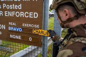U.S. Air Force Staff Sgt. Ian Eckert, 422nd Security Forces Squadron flight sergeant, changes a FPCON sign