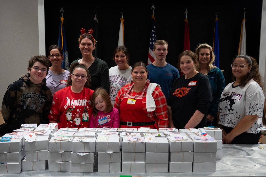 Volunteers pose for a group photo during the first packaging day of the Cookie Caper at the Powell Event Center, Goodfellow Air Force Base, Texas, Dec. 2, 2025. Volunteers packaged over 15,000 cookies for the trainees and first-term service members stationed at Goodfellow. (U.S. Air Force photo by Senior Airman Brian Lummus)