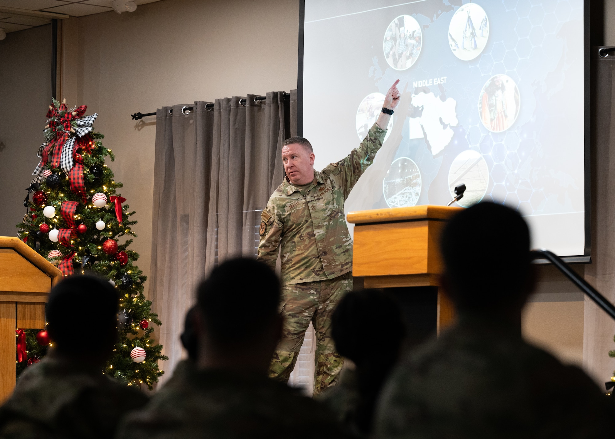 Chief Bickley points at a projected image while speaking to Airmen during an all-call brief.