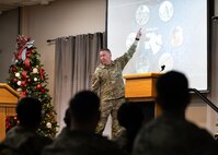 Chief Bickley points at a projected image while speaking to Airmen during an all-call brief.