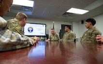 Chief Bickley listens to a briefing at a table with other Airmen.