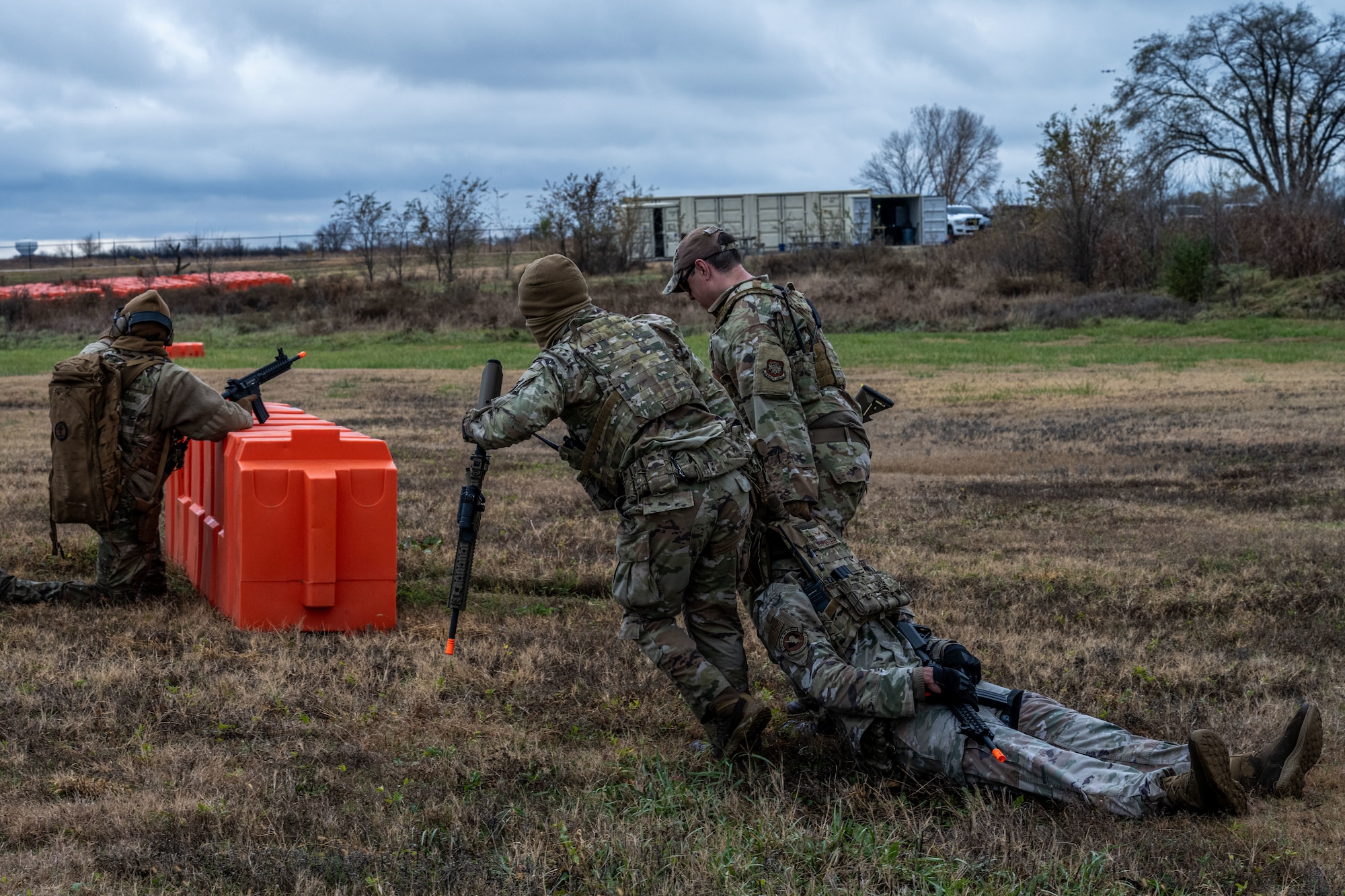 22nd Security Forces Squadron Airmen drag a simulated casualty behind barriers while under simulated fire at McConnell Air Force Base, Kansas, Nov. 21, 2025. Defenders used this exercise to practice casualty care training during close quarters battle scenarios. (U.S. Air Force photo by Senior Airman Paula Arce)