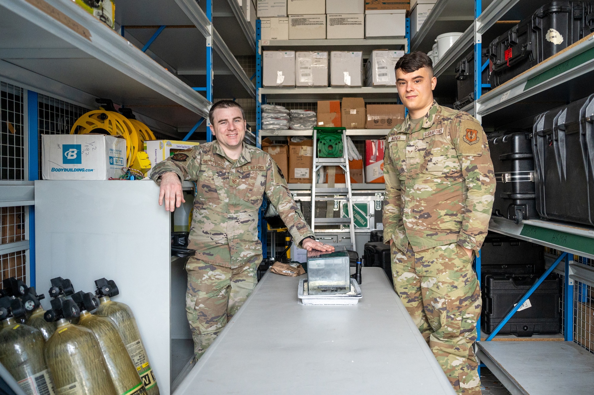 U.S. Air Force Tech. Sgt. Alex Shuttleworth, 86th Operational Medical Readiness Squadron bioenvironmental flight noncommissioned officer in charge and Senior Airman Brandon Wagner, 86th OMRS bioenvironmental engineering technician, stand alongside a radiation cloud chamber tank at Ramstein Air Base, Germany, Nov. 24, 2025.