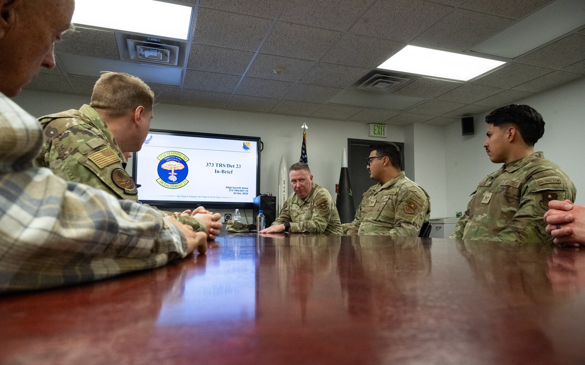 Chief Bickley listens to a briefing at a table with other Airmen.
