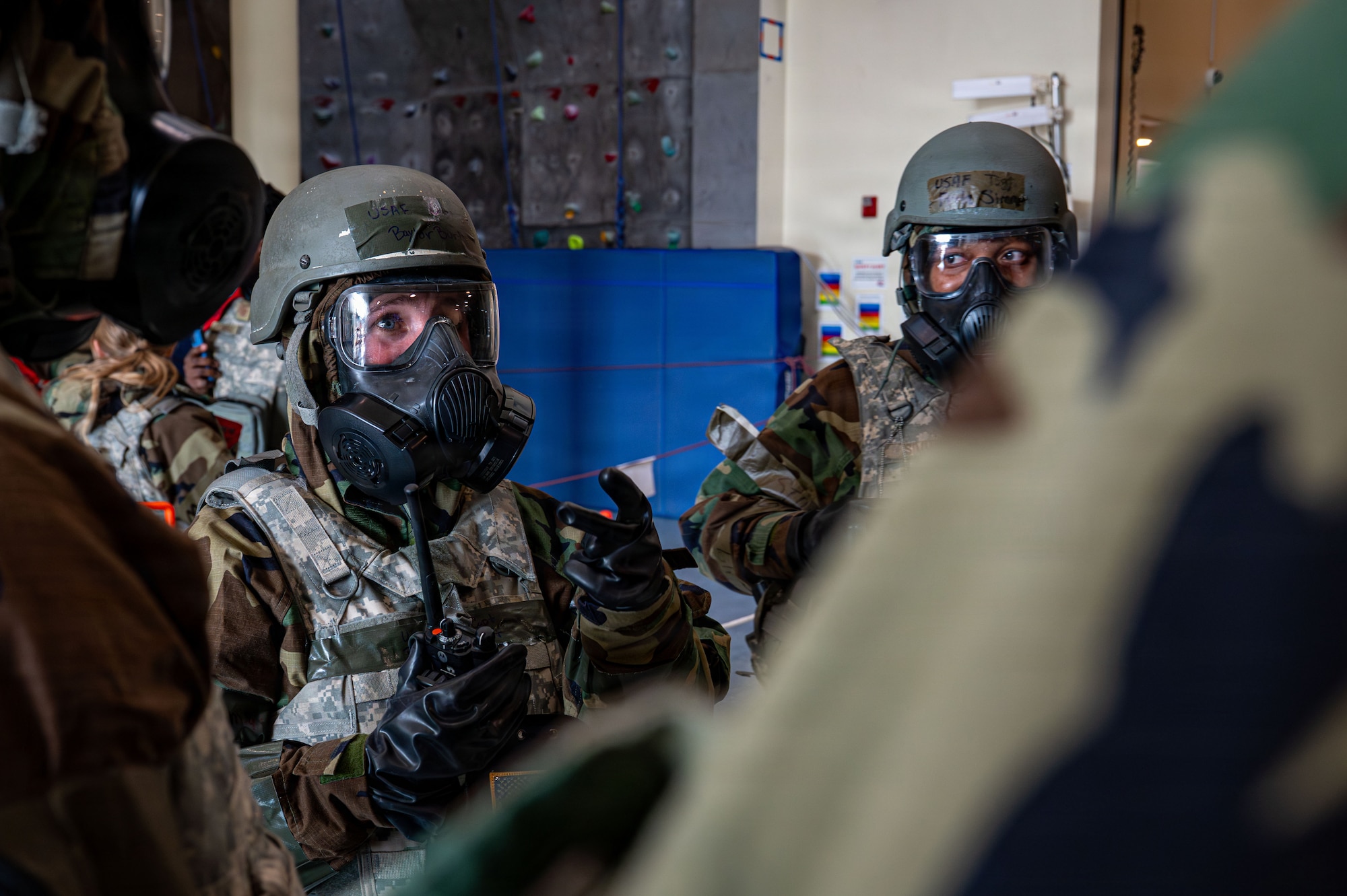 An Air Force member in a gas mask talks to a group