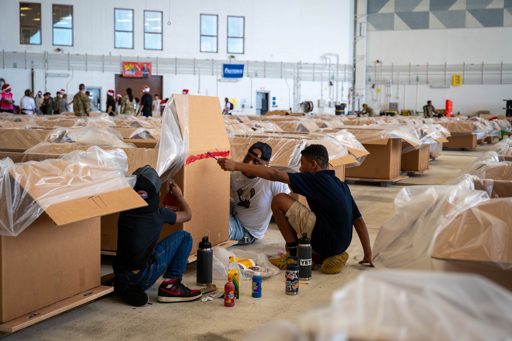 Service members and volunteers from multiple nations begin to prepare and build airdrop bundles.