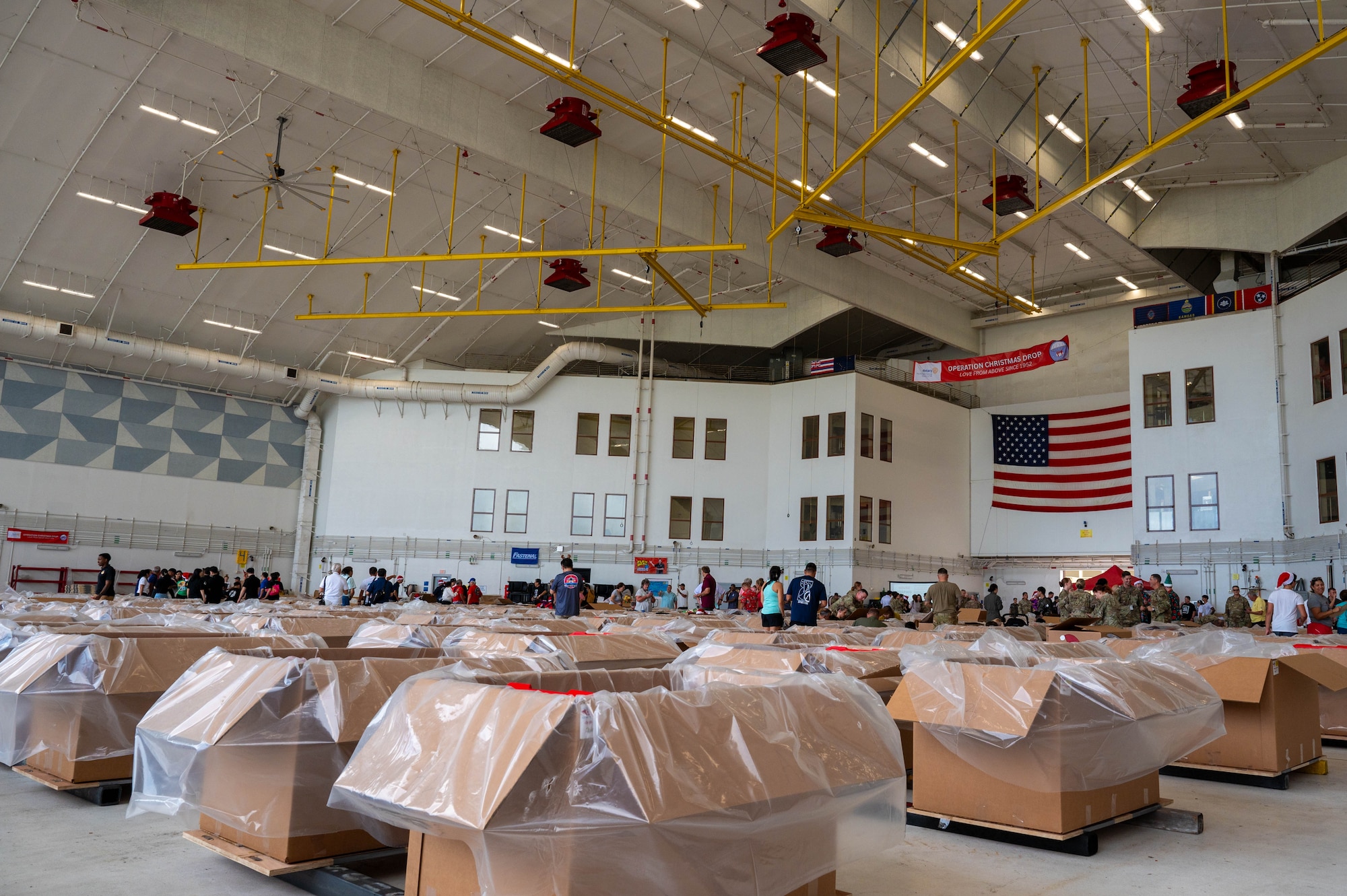 Service members and volunteers from multiple nations prepare and build airdrop bundles.