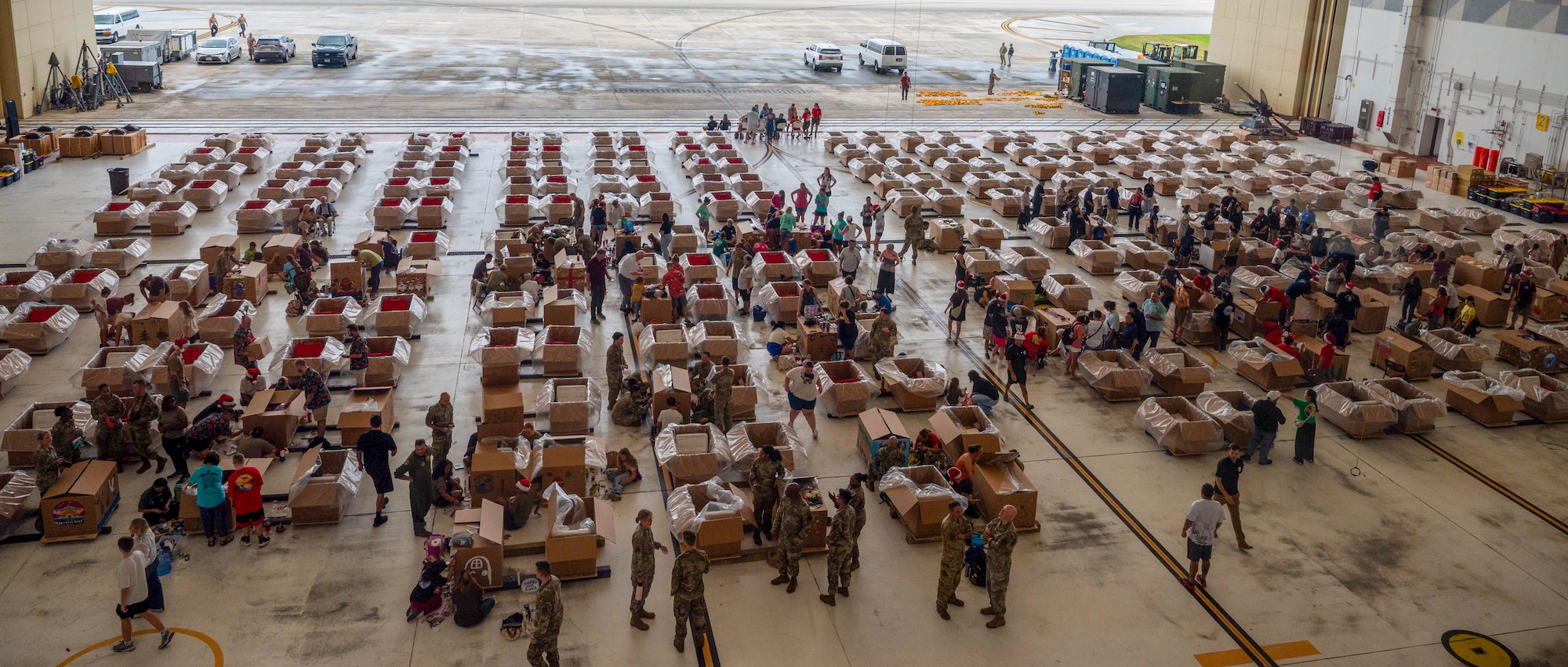Service members and volunteers from multiple nations prepare and build airdrop bundles.
