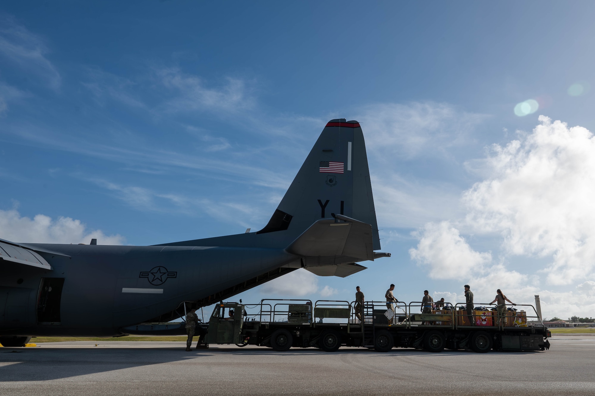 Military members load a C-130J aircraft with boxes.