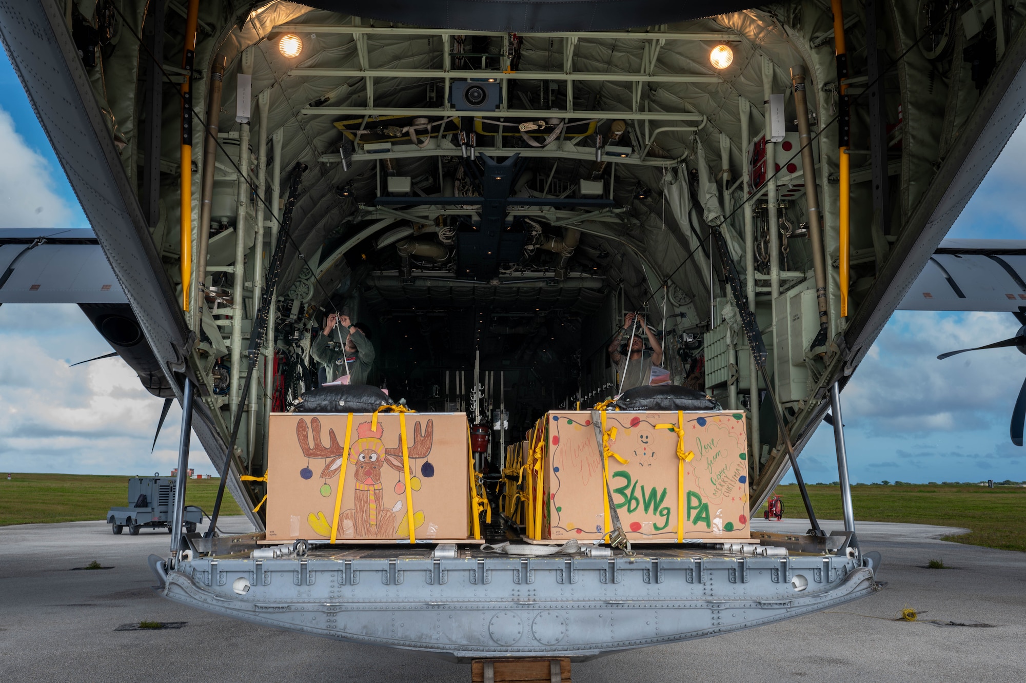 Two Airmen secure boxes onto a C-130J aircraft.