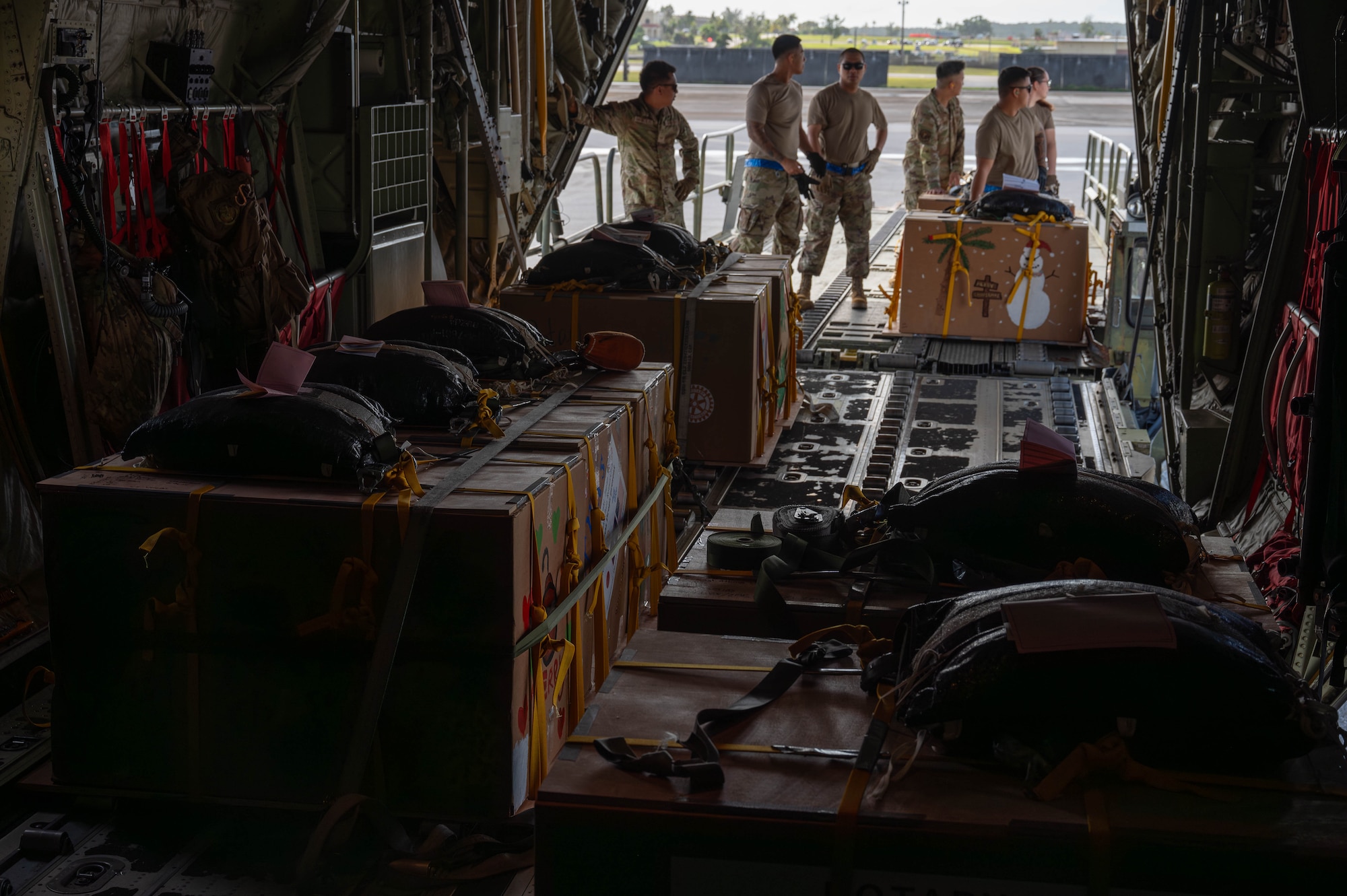 Airmen load bundles of boxes onto a C-130 aircraft.