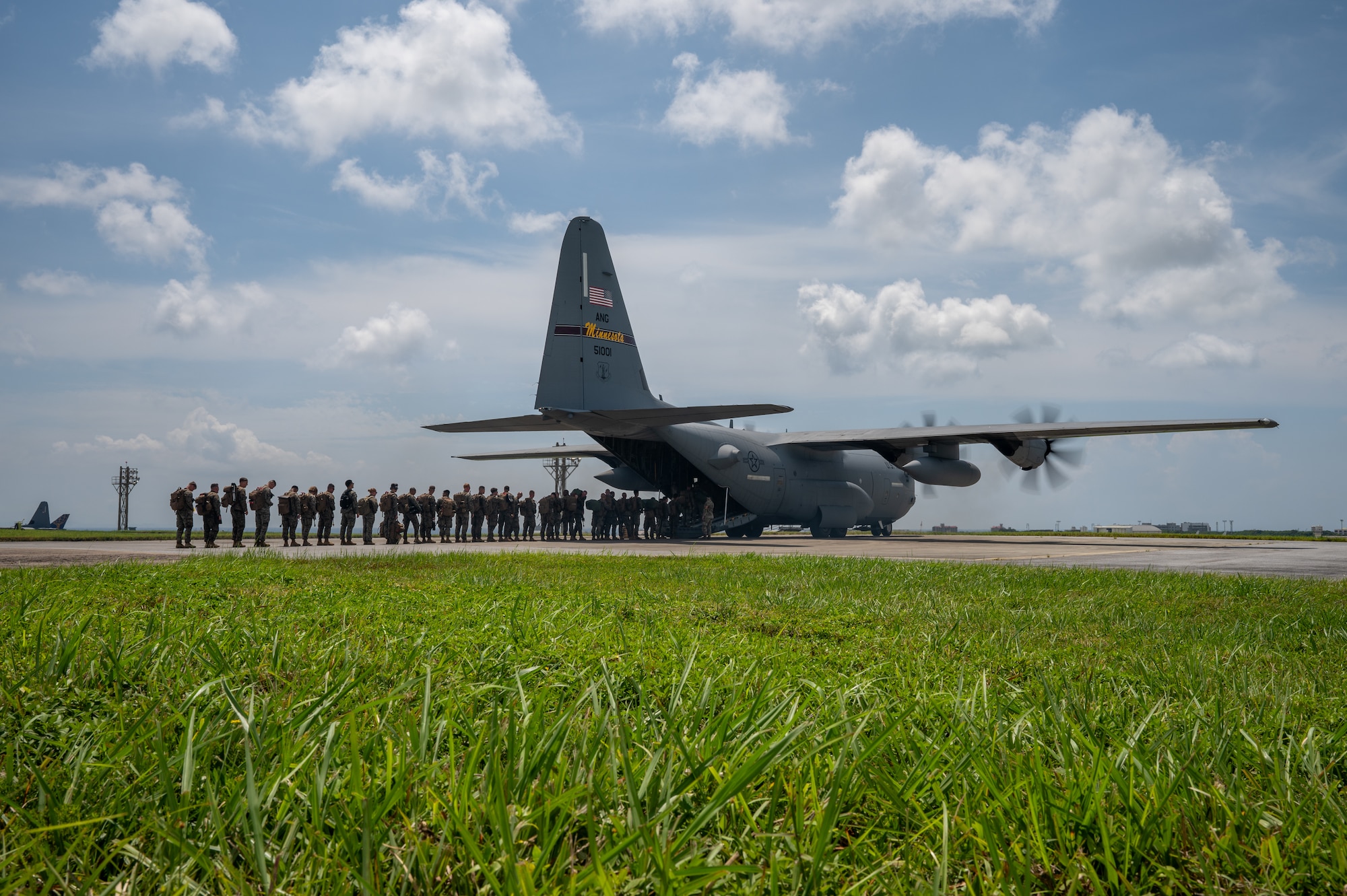 uniformed members line up to board a aircraft view from far away in the grass