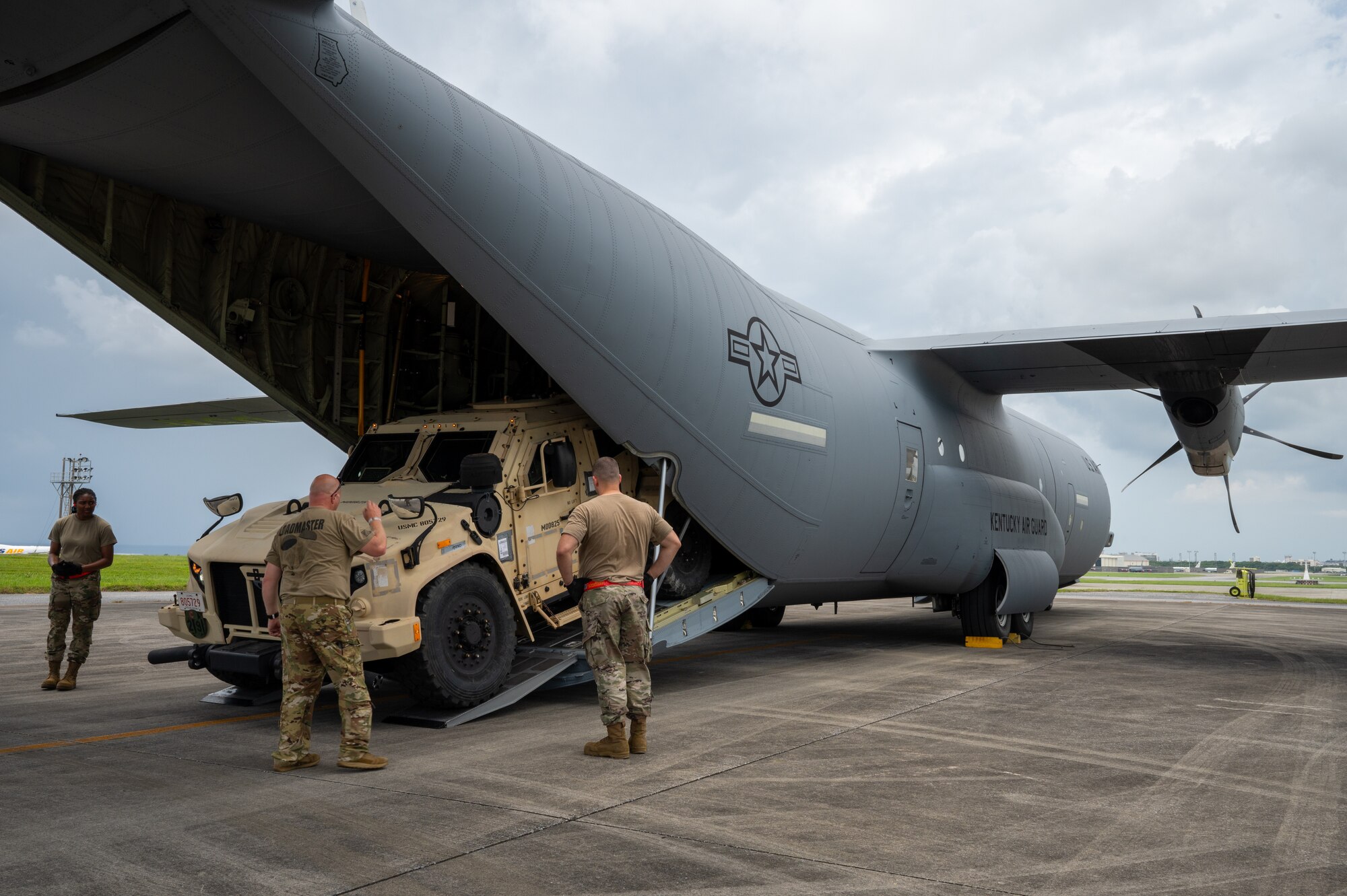 Uniformed members help board a tactical vehicle into the back of an aircraft