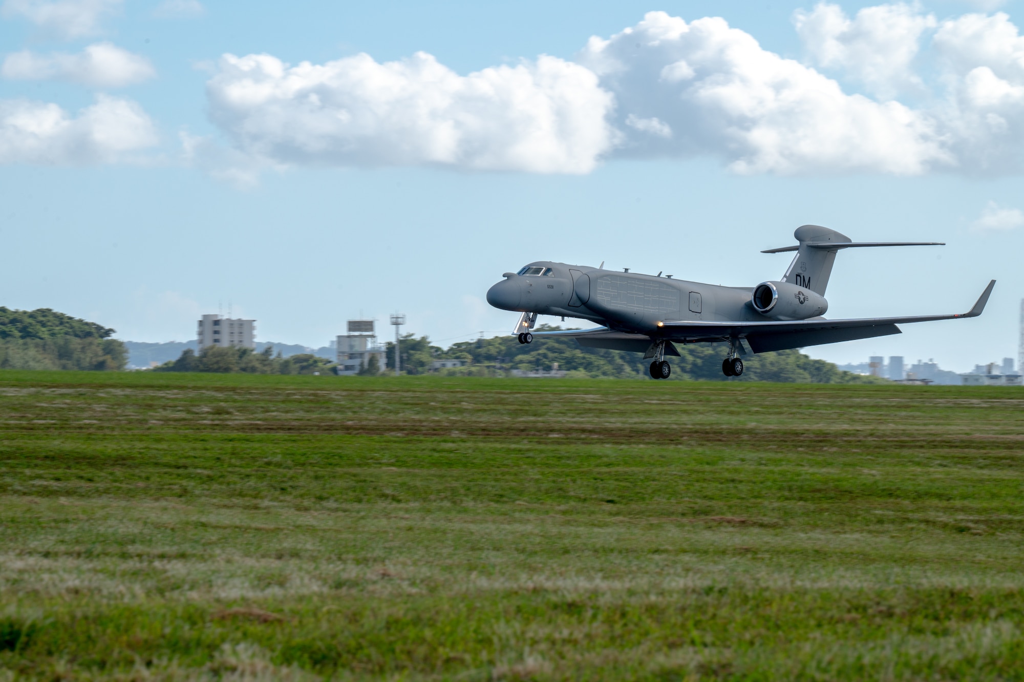 The left side of a light grey aircraft as it lands on the runway