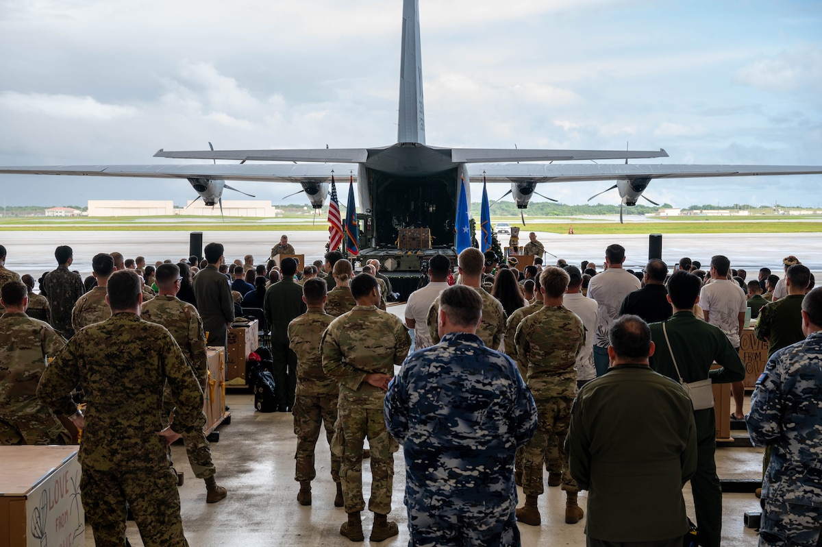 Military members and guests look toward a stage.