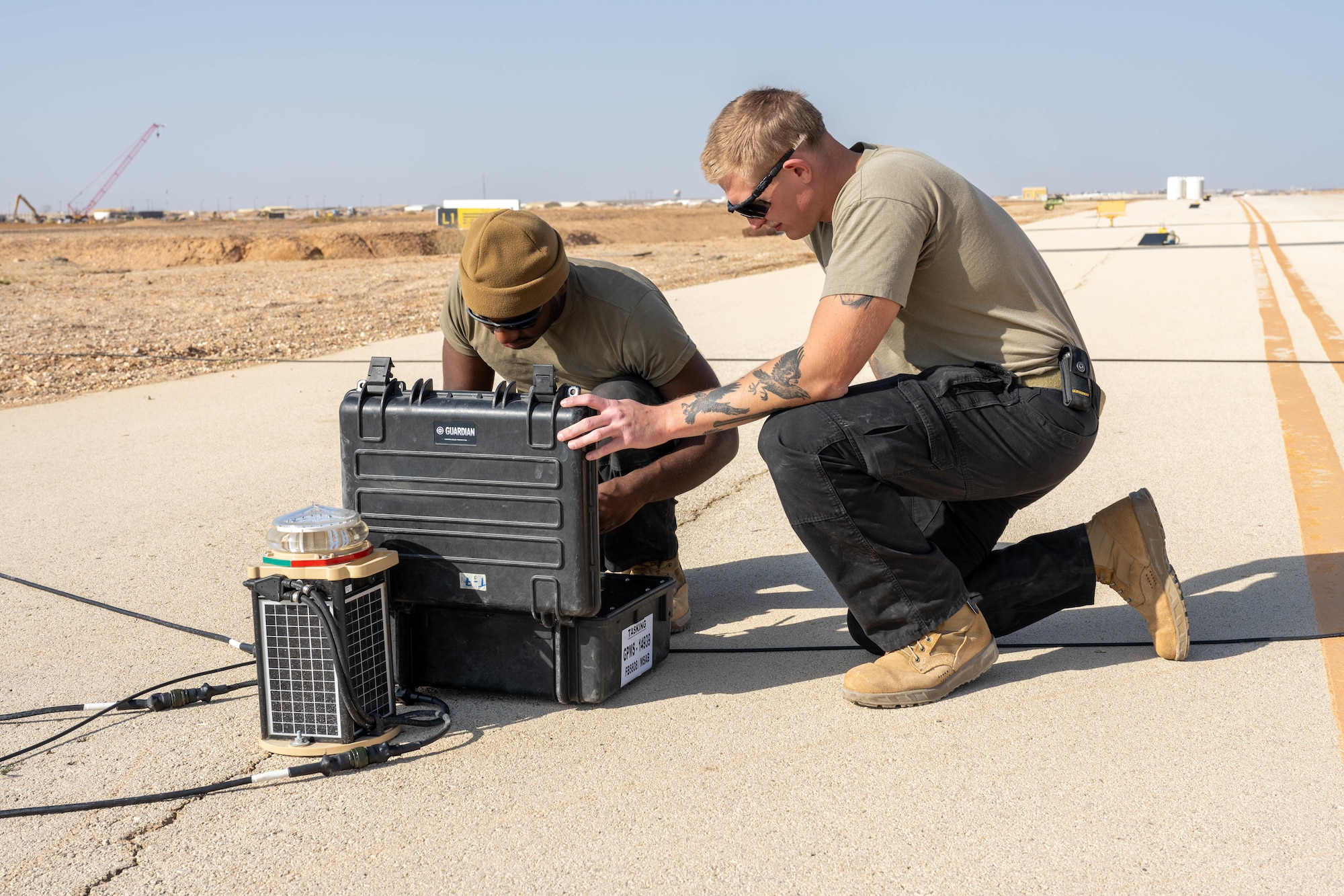 U.S. Air Force Senior Airman Gregory Curry, 332nd Expeditionary Civil Engineer Squadron electrical journeyman, left, and Senior Airman Logan Landon, 332nd ECES electrical journeyman, operate a runway lighting system computer in the U.S. Central Command area of responsibility, Nov. 19, 2025. Installing the upgraded lights gave the ECES Airmen an opportunity to learn how to install lights on a bi-directional runway for the first time in their careers. (U.S. Air Force photo by Senior Airman Kari Degraffenreed)