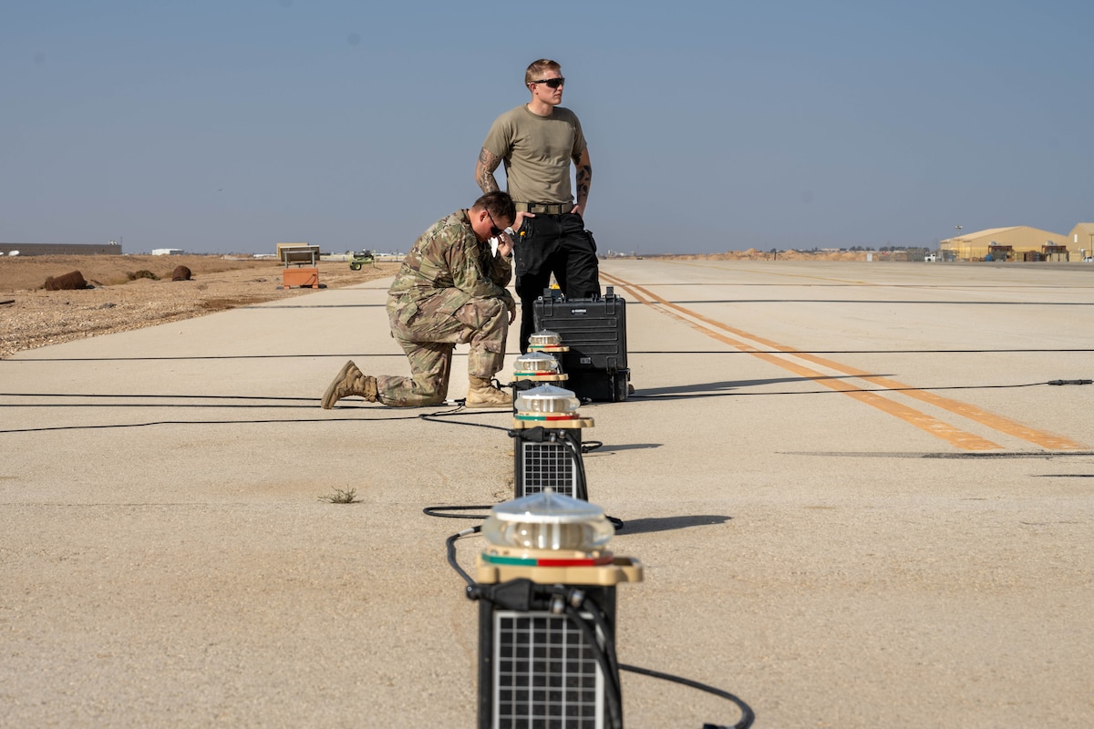U.S. Air Force Senior Airman Treigh Boedigheimer, 332nd Expeditionary Civil Engineer Squadron electrical journeyman, left, and Senior Airman Logan Landon, 332nd ECES electrical journeyman, install upgraded lights on a runway in the U.S. Central Command area of responsibility, Nov. 19, 2025. Designed to cut through the region’s frequent dust and haze, the upgraded lights offer stronger, adjustable visibility for all airfield traffic. (U.S. Air Force photo by Senior Airman Kari Degraffenreed)