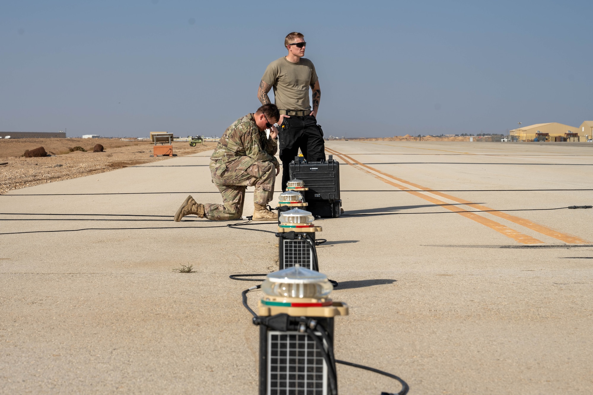 U.S. Air Force Senior Airman Treigh Boedigheimer, 332nd Expeditionary Civil Engineer Squadron electrical journeyman, left, and Senior Airman Logan Landon, 332nd ECES electrical journeyman, install upgraded lights on a runway in the U.S. Central Command area of responsibility, Nov. 19, 2025. Designed to cut through the region’s frequent dust and haze, the upgraded lights offer stronger, adjustable visibility for all airfield traffic. (U.S. Air Force photo by Senior Airman Kari Degraffenreed)