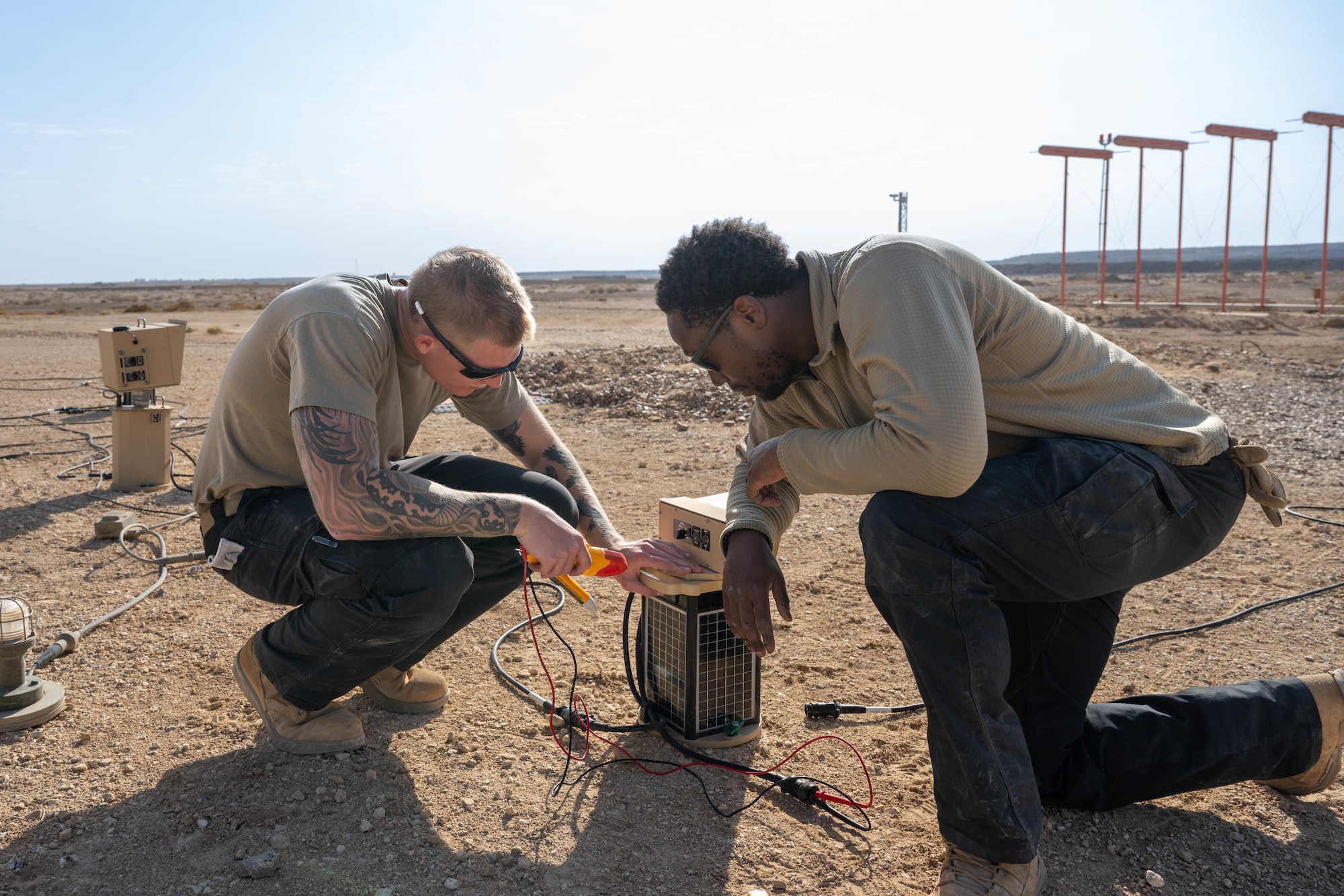 U.S. Air Force Senior Airman Logan Landon, 332nd Expeditionary Civil Engineer Squadron electrical journeyman, left, checks the battery power of a runway lighting system with Senior Airman Kyle Deboious, 332nd ECES electrical journeyman, in the U.S. Central Command area of responsibility, Nov. 19, 2025. The new LED lights are energy-efficient, safer to use, and powered by 120-volt outlets, simplifying installation and upkeep. (U.S. Air Force photo by Senior Airman Kari Degraffenreed)