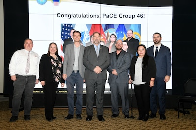 Seven people a mix of men and women stand looking at the camera.