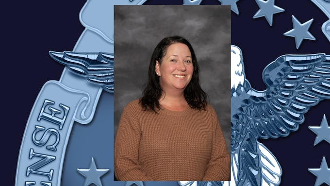 Headshot of woman with dark shoulder-length hair wearing tan shirt