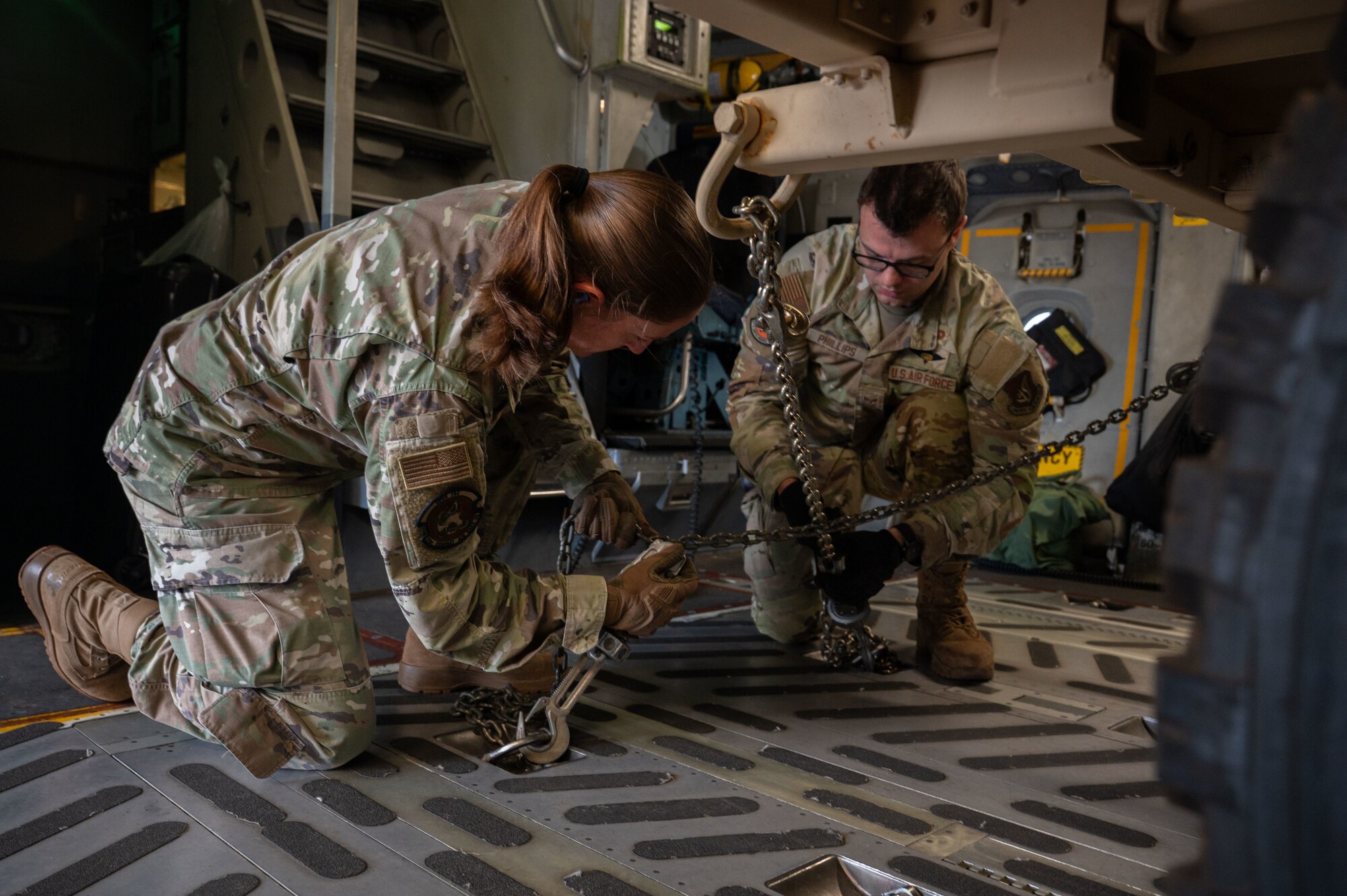 U.S. Air Force Staff Sgt. Sarah Vrachalus, 21st Combat Air Base Squadron traffic management office specialist, tightens chains while loading a U.S. Army Humvee on to a U.S. Air Force C-17 Globemaster III during Joint Pacific Multinational Readiness Center 26-01 at Wheeler Army Airfield, Hawaii, Nov. 9, 2025. JPMRC 26-01 supported the 21st ATF’s objective to execute rapid force flow in contested environments. (U.S. Air Force photo by Senior Airman Alondra Cristobal Hernandez)