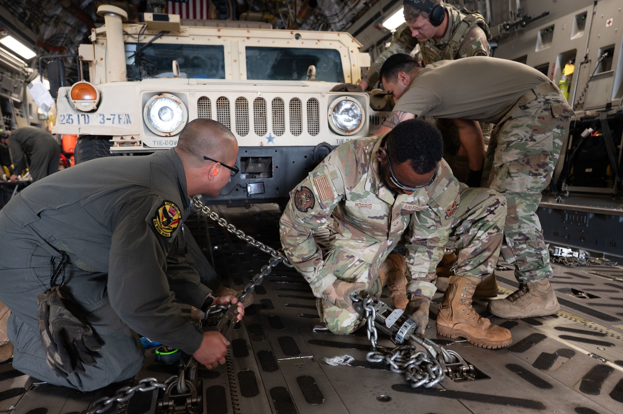 U.S. Air Force Airmen from the 21st Combat Air Base Squadron and 154th Wing, Hawaii Air National Guard, tighten chains while loading a U.S. Army Humvee into a U.S. Air Force C-17 Globemaster III during Joint Pacific Multinational Readiness Center 26-01 at Wheeler Army Airfield, Hawaii, Nov. 9, 2025. During JPMRC 26-01, the 21st Air Task Force leveraged innovation and training to overcome operational challenges in support of Agile Combat Employment in the Indo-Pacific. (U.S. Air Force photo by Senior Airman Alondra Cristobal Hernandez)