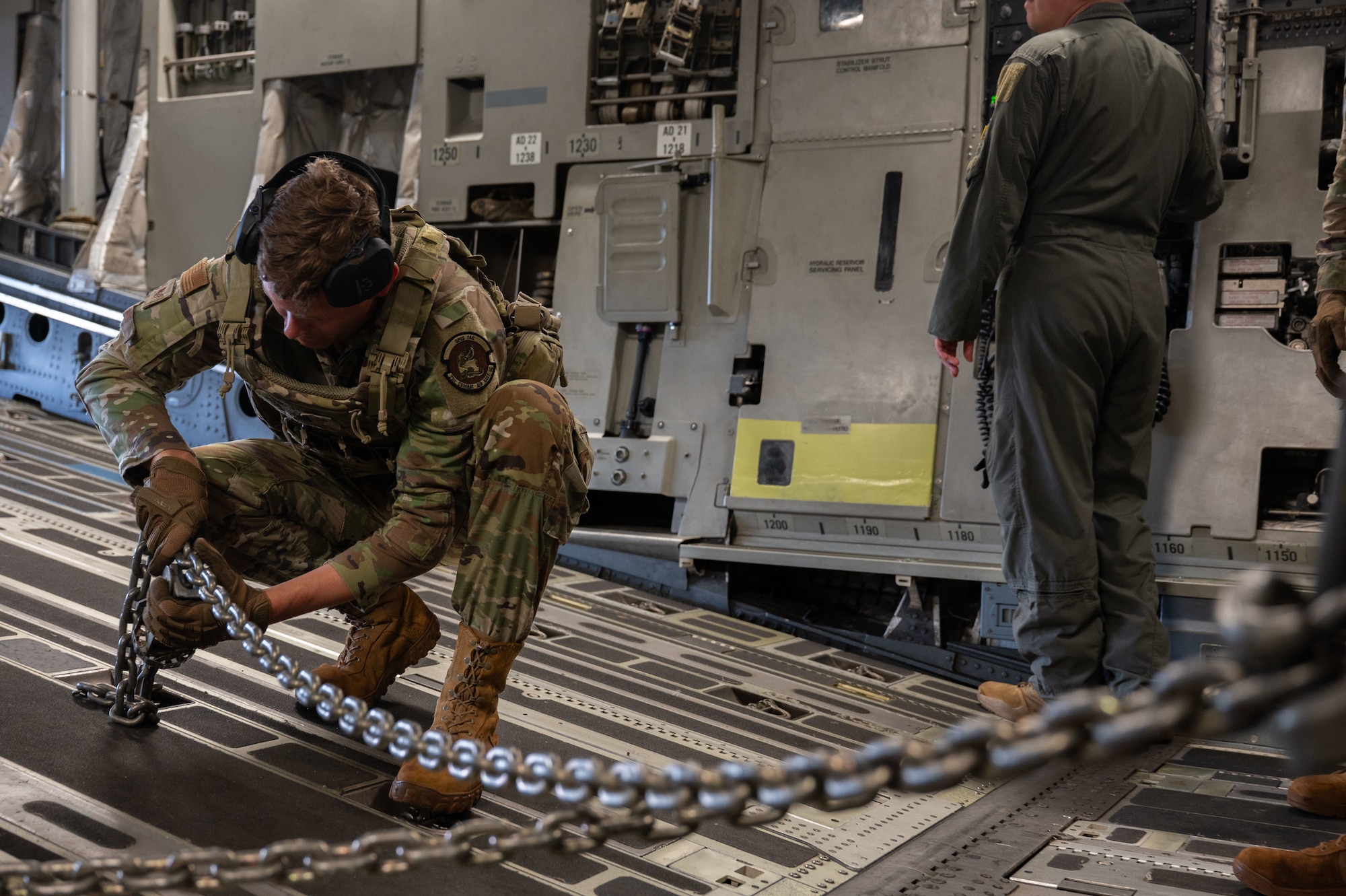 U.S. Air Force Staff Sgt. Conner Craig, 21st Combat Air Base Squadron engineering specialist, tightens chains while loading a U.S. Army Humvee into a U.S. Air Force C-17 Globemaster III during Joint Pacific Multinational Readiness Center 26-01 at Wheeler Army Airfield, Hawaii, Nov. 9, 2025. During JPMRC 26-01, the 21st Air Task Force leveraged innovation and training to overcome operational challenges in support of Agile Combat Employment in the Indo-Pacific. (U.S. Air Force photo by Senior Airman Alondra Cristobal Hernandez)