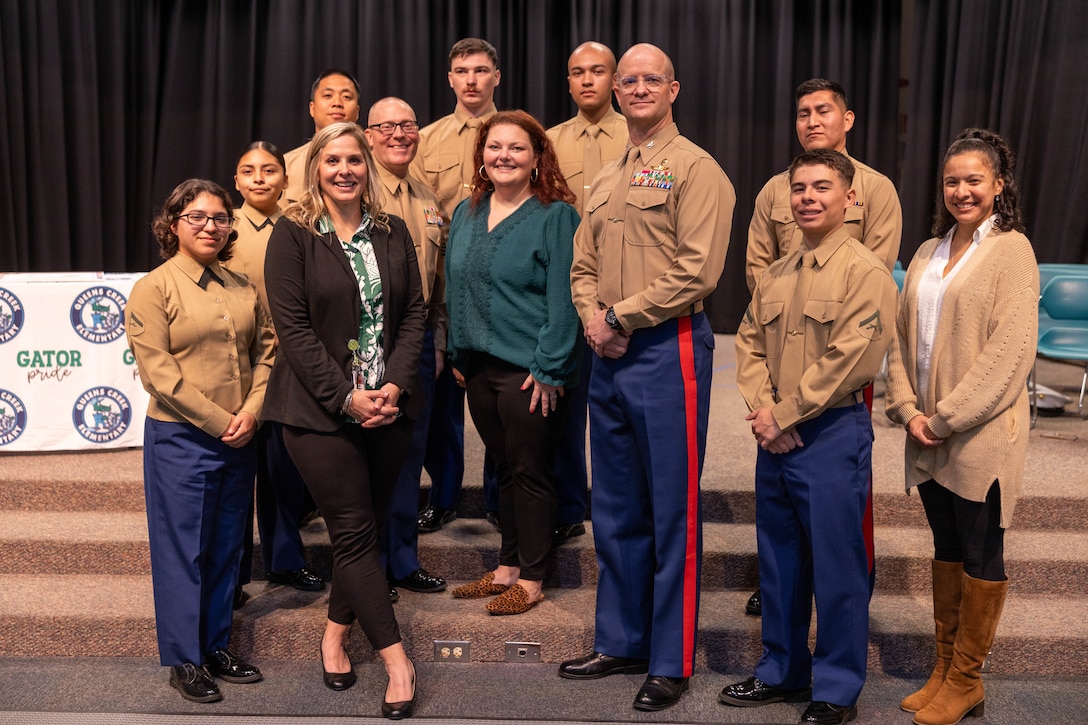 U.S. Marines with II Marine Expeditionary Force Information Group pose for a photo with staff members of Queens Creek Elementary School during an Adopt-a-School ceremony at Queens Creek Elementary School in Swansboro, North Carolina, Dec. 2, 2025. The Adopt-a-School program is a voluntary program between Queens Creek Elementary School and II MIG designed to strengthen the connection between the military and local community. (U.S. Marine Corps photo by Lance Cpl. Dorian Melrath)