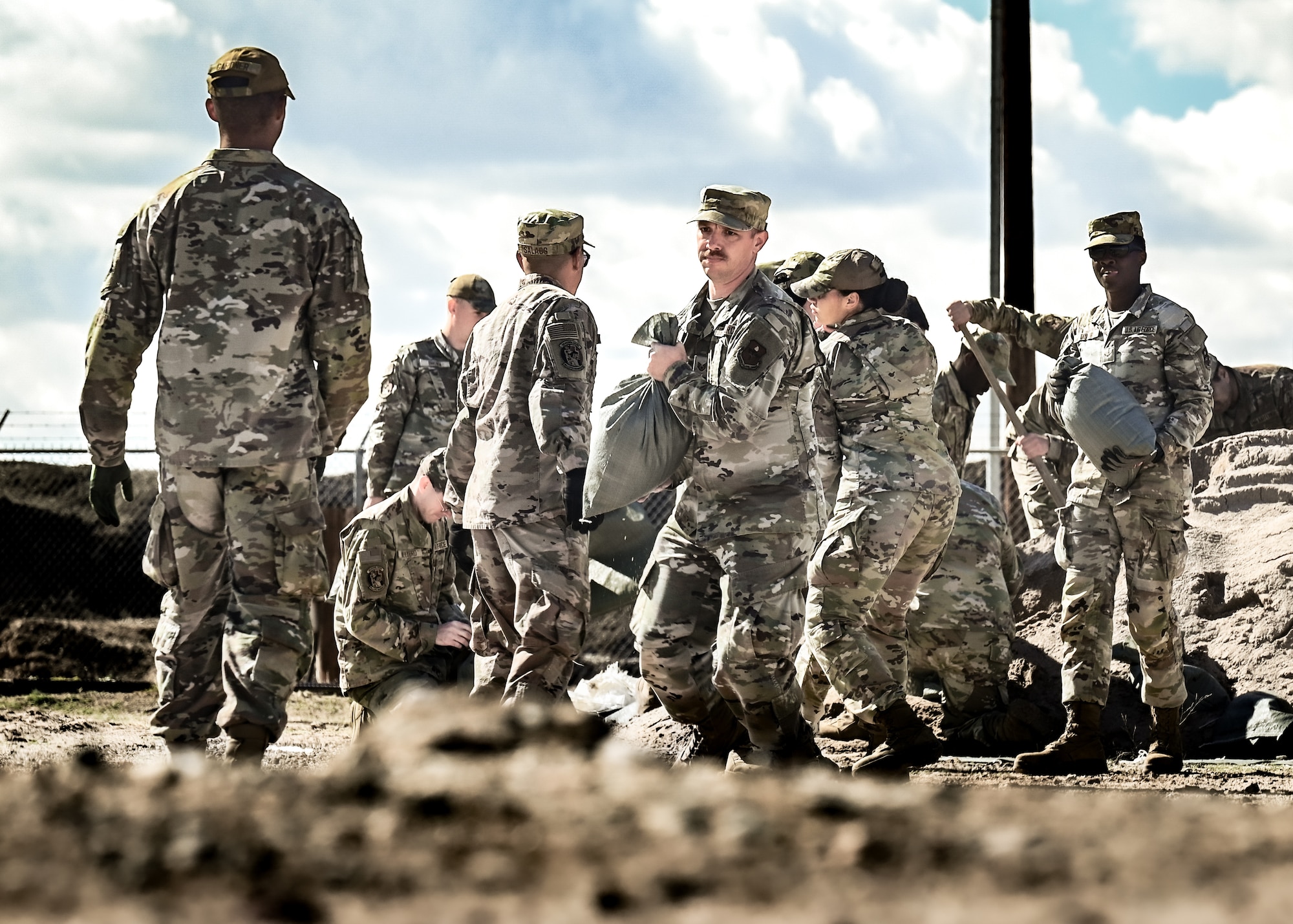 U.S. Air Force Airmen assigned to the 56th Civil Engineer Squadron shovel and pack bags of dirt to construct a defensive firing post as part of the Prime Base Engineer Emergency Force readiness challenge