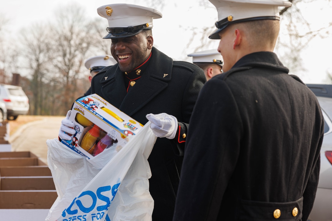 U.S. Marine Corps Lance Cpl. Mathew Alston, an administrative specialist with 4th Light Armored Reconnaissance Battalion, places donated toys in a collection bin during the Toys for Tots toy drive in Arlington, Virginia, Dec. 6, 2025.  The basic mission of the Marine Toys for Tots Program is to collect new unwrapped toys and distribute those toys to less fortunate children during the holidays. (U.S. Marine Corps photo by Lance Cpl. David Brandes)