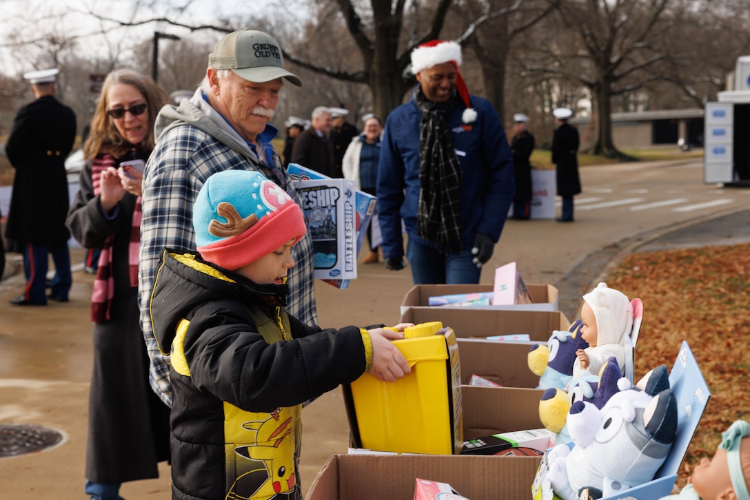 A child puts a toy in a collection bin during the Toys for Tots toy drive in Arlington, Virginia, Dec. 6, 2025.  The basic mission of the Marine Toys for Tots Program is to collect new unwrapped toys and distribute those toys to less fortunate children during the holidays. (U.S. Marine Corps photo by Lance Cpl. David Brandes)