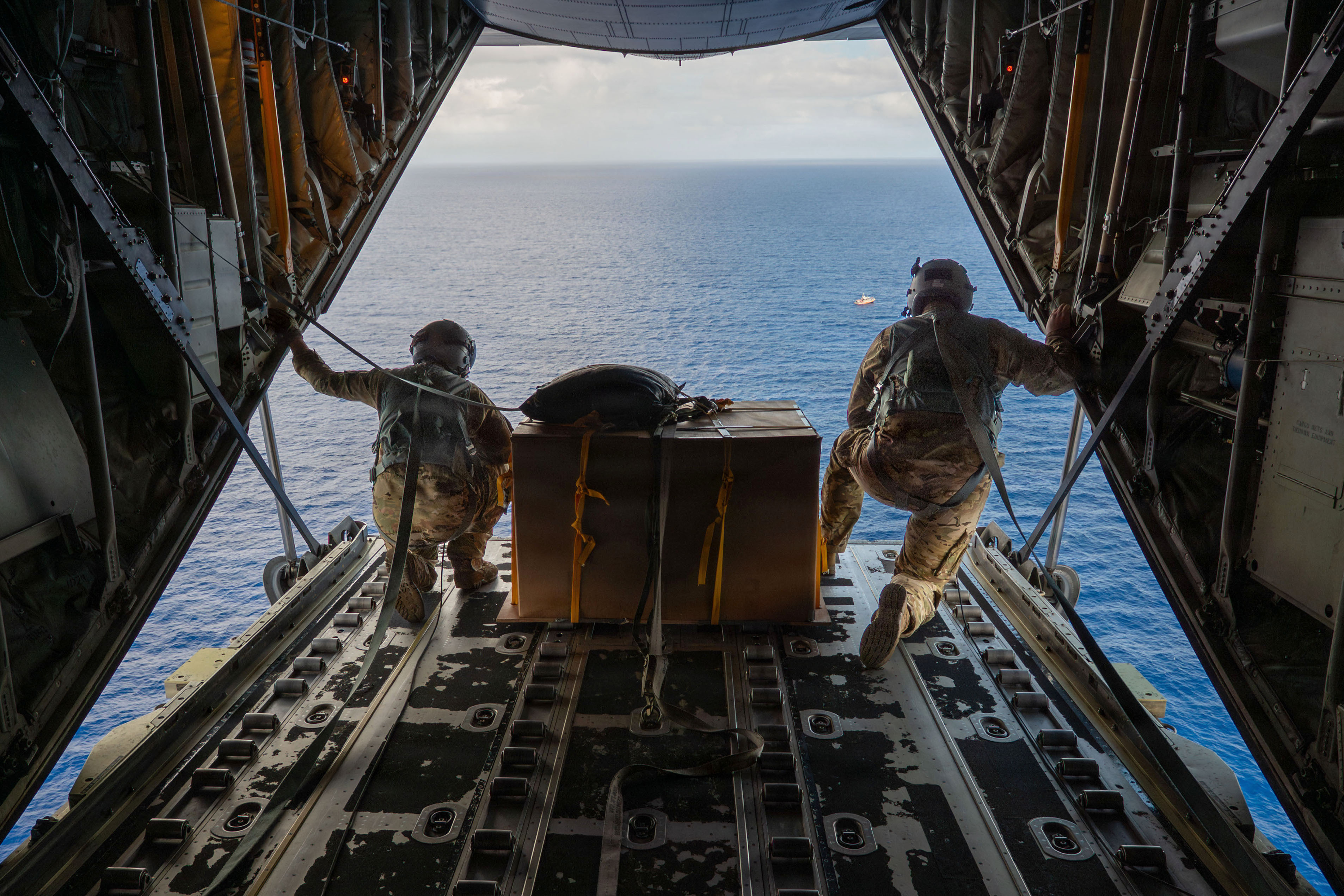 A person on Tamatam, Micronesia, runs to retrieve bundles air-dropped from a U.S. Air Force C-130J Super Hercules aircraft during Operation Christmas Drop, Dec. 12, 2024.