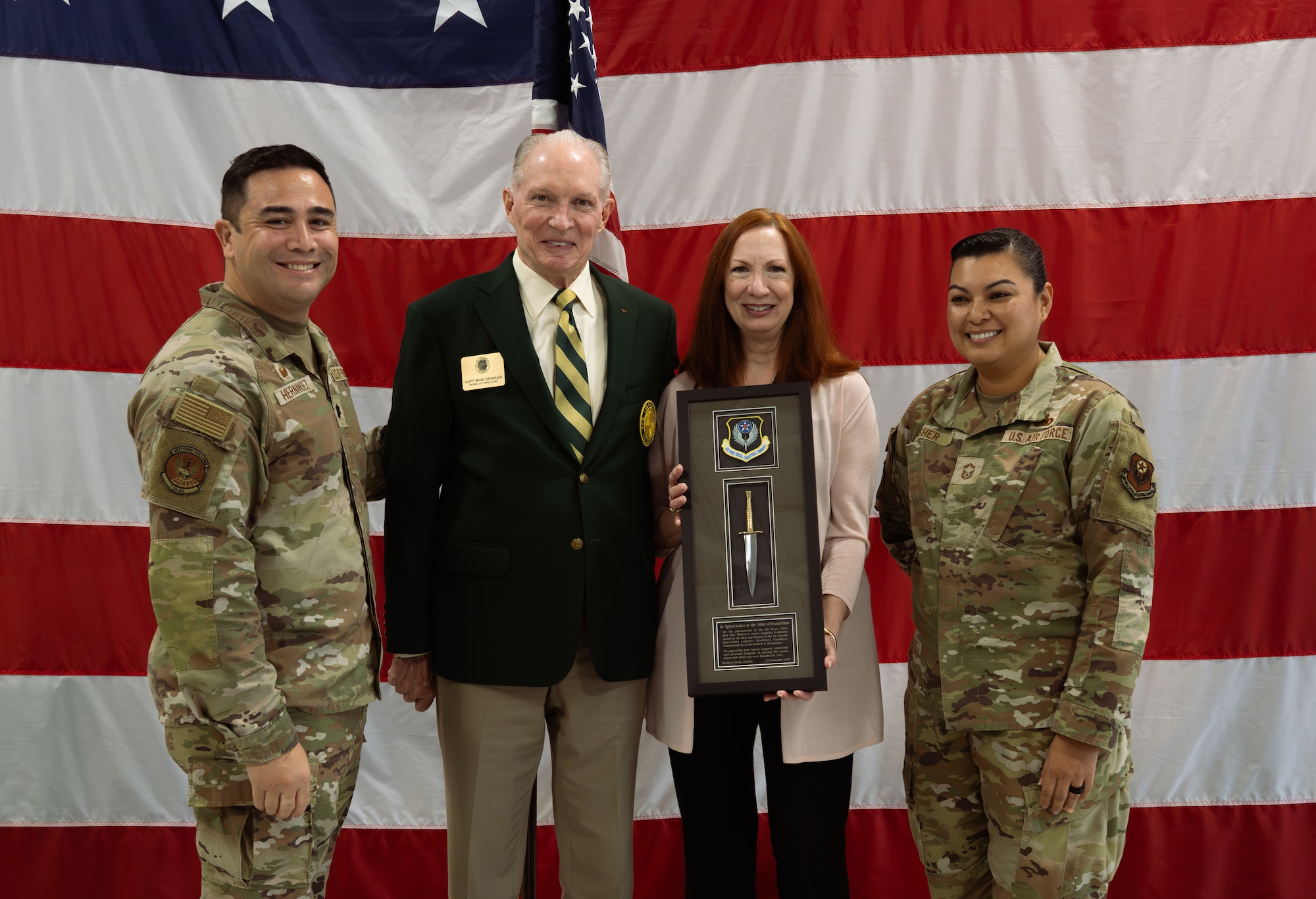 Lt. Col. Garrett Hernandez, 1st Special Operations Wing Logistics Readiness Squadron commander, far left, and Senior Master Sgt Karen Fisher, 1 SOLRS senior enlisted leader, far right, present retired U.S. Navy Capt. Mike Denkler, an Order of Daedalians director, with a thank-you gift at Hurlburt Field, Florida, Nov. 24, 2025.