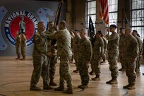 Lt. Col. Andrew V. Salmo, outgoing commander of the 1st Battalion, 178th Infantry Regiment, passes the battalion guidon to Col. Michael Kowalski, commander of the 33rd Infantry Brigade Combat Team.