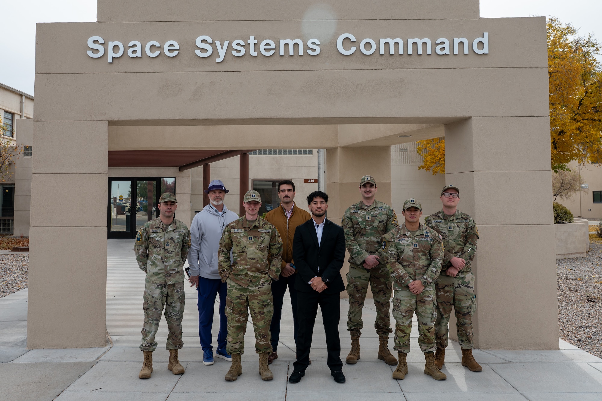 People pose for a group photo in front of a building