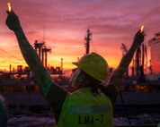 Boatswain’s Mate 2nd Class Ruben Zavala, assigned to the America-class amphibious assault ship USS Tripoli (LHA 7) signals to the Kaiser-class underway replenishment oiler USNS Tippecanoe (T-AO 199) during a replenishment-at-sea in the South China Sea, Dec. 6, 2025.