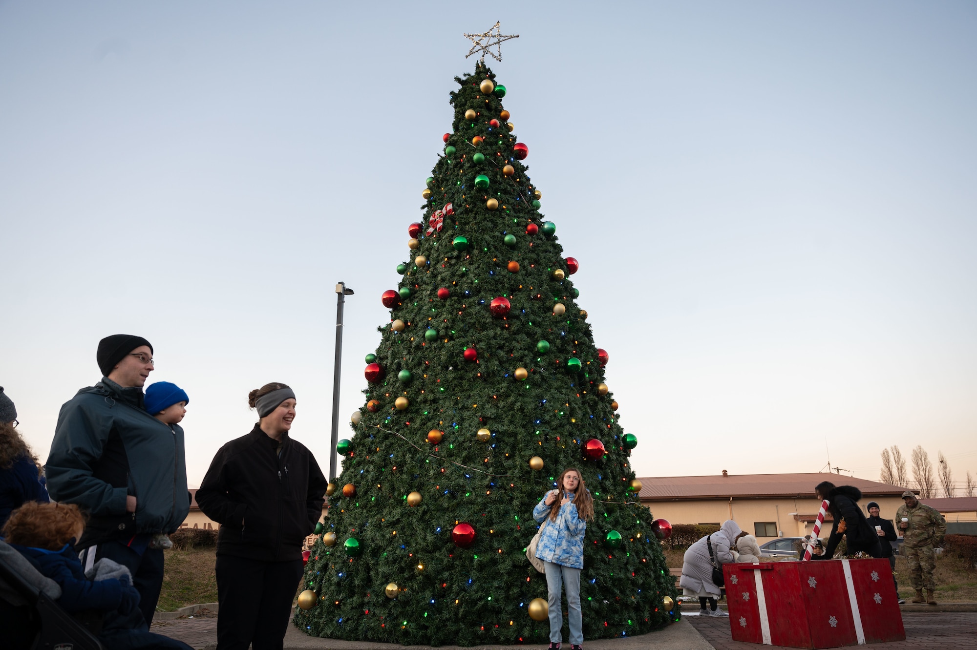 Members of the Osan community gather during the Christmas Tree Lighting Ceremony outside the base theater at Osan Air Base, Republic of Korea, Dec. 5, 2025. The gathering reinforced community values and reminded Airmen they remain part of a larger Team Osan family while stationed overseas. (U.S. Air Force photo by Senior Airman Rome Bowermaster)