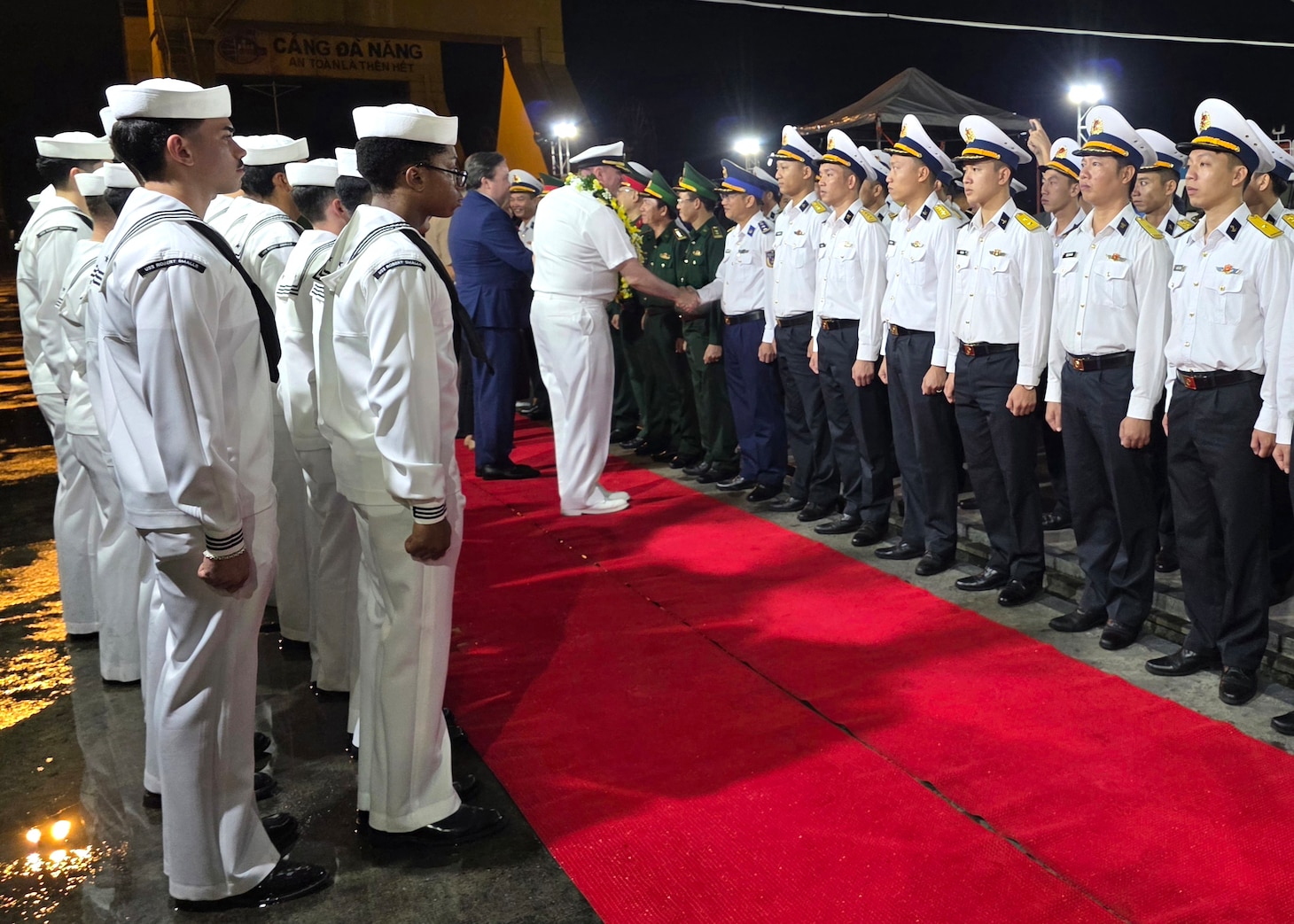 Capt. Stephen Henz, commanding officer of the Ticonderoga-class guided-missile cruiser USS Robert Smalls (CG 62), center, and Ambassador Marc E. Knapper, the U.S. Ambassador to Vietnam, center-left, shake hands with members of the Vietnam People's Navy during an arrival ceremony for a port visit to Da Nang, Vietnam, Dec. 8, 2025.