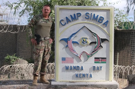 U.S. Air Force Chief Master Sgt. Frank Rawls stands in front of the Camp Simba sign for a photo while being deployed to Operation OCTAVE SHIELD at Manda Bay, Kenya, March 22, 2022.