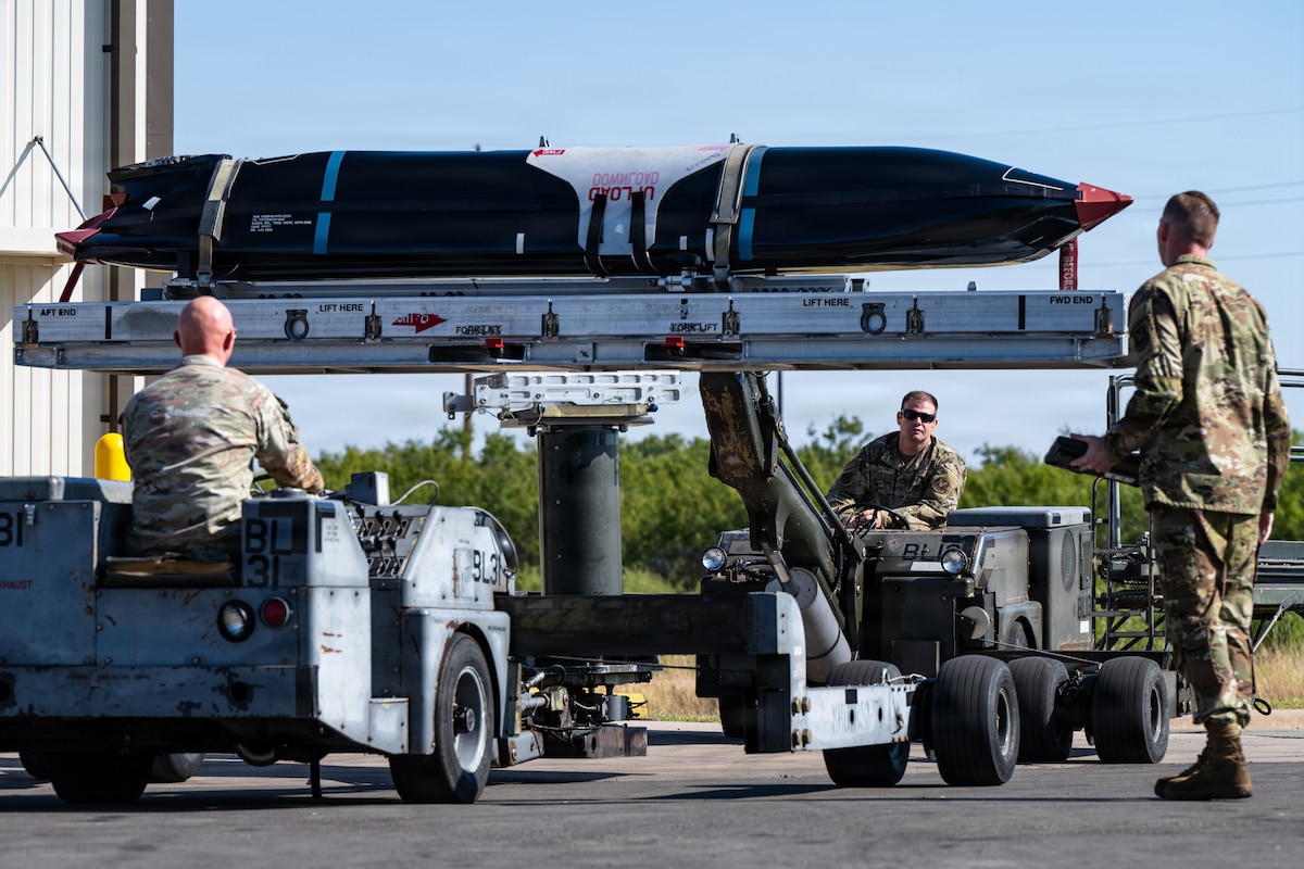 From left, U.S. Air Force Tech. Sgts. Aleczandro Perez and Dawson Bailey, 7th Maintenance Group load standardization crewmembers, transport an AGM-158C Long Range Anti-Ship Missile while supervised by Tech. Sgt. Earl Campbell, 7th MXG loading standardization crew chief, at Dyess Air Force Base, Texas, Sept. 15, 2025. Routine training maintains proficiency in weapons handling procedures, ensuring the 7th Bomb Wing's ability to deliver decisive combat power when called upon. (U.S. Air Force photo by Senior Airman Jade M. Caldwell)