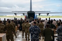 Military members and guests look toward a stage.