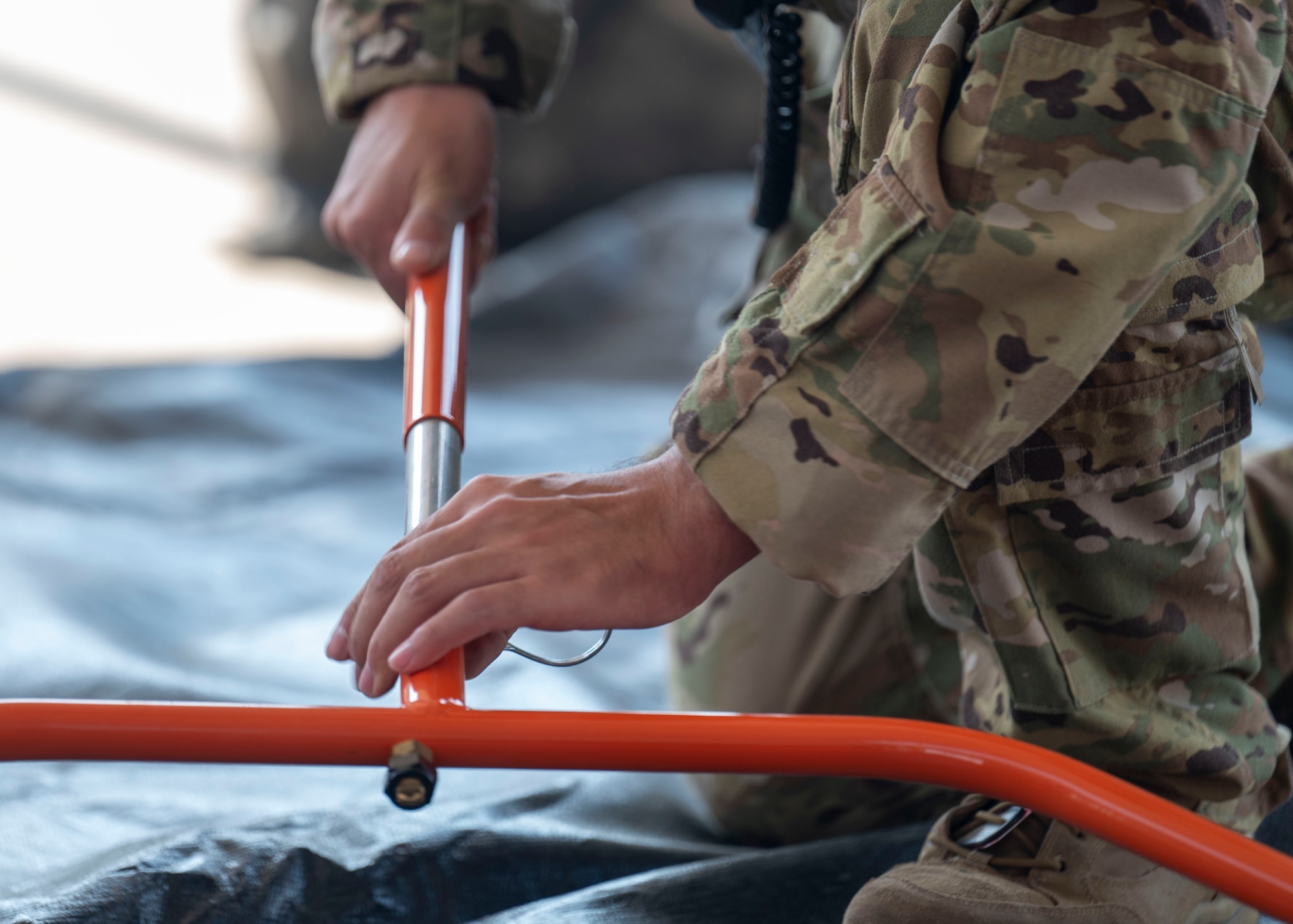 A man in a military uniform assembles a metal hoop.
