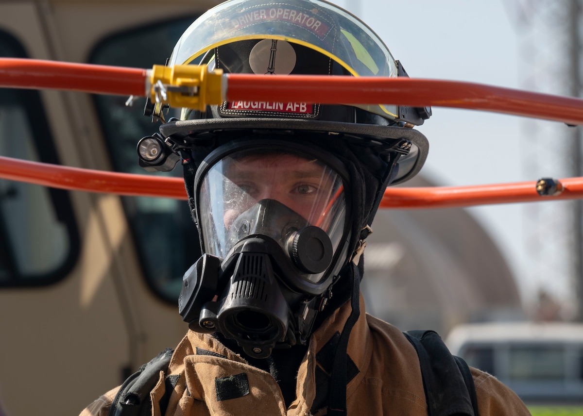 A metal hoop is held above the head of a man in a firefighter uniform.